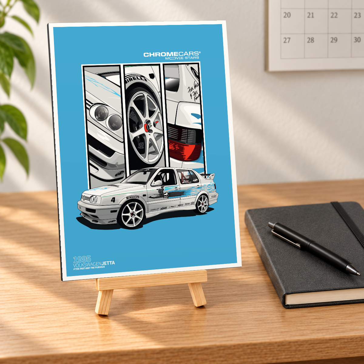 Mockup in nahezu frontaler Ansicht: Kleine hochformatige Alu-Dibond-Bildplatte auf einer Holzstaffelei auf einem hellen Holzschreibtisch. Das Motiv zeigt den weißen VW Jetta „Jesse’s Jetta“ mit blauen Dekoren vor türkisblauem Hintergrund sowie drei Detailfelder mit Scheinwerfern, Felge und Rücklicht. Schwarzes Notizbuch mit Stift, Wandkalender und Pflanze dienen als Szenerie.