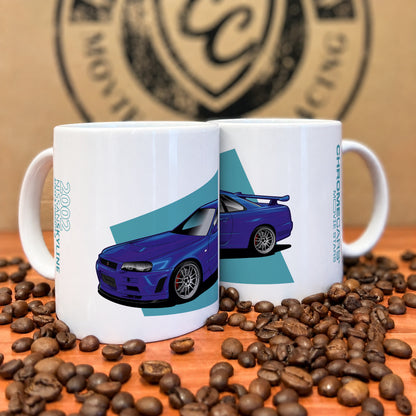Zwei weiße Tassen mit blauem Nissan-Skyline-R34-Motiv zwischen Kaffeebohnen.