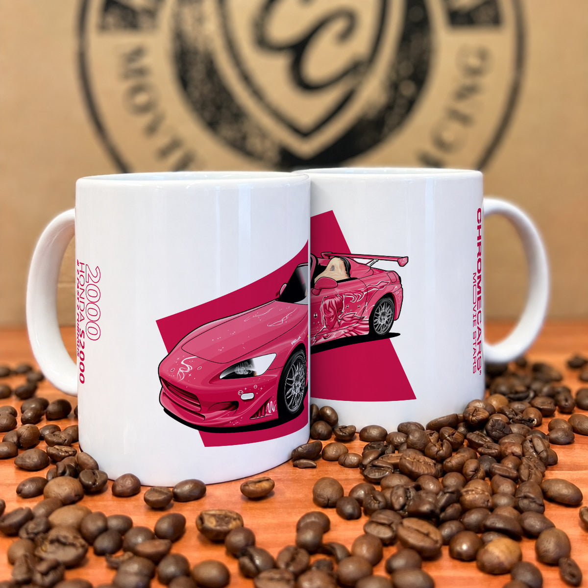 Zwei weiße Tassen mit pinkfarbenem Honda-S2000-Motiv zwischen Kaffeebohnen.