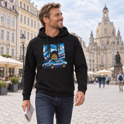 Mann im schwarzen Hoodie steht mit einer Karte auf einem Altstadtplatz vor einer großen Kirche. Vorn zeigt der Hoodie ein blaues Auto mit goldfarbenen Rädern und drei Detailfelder.
