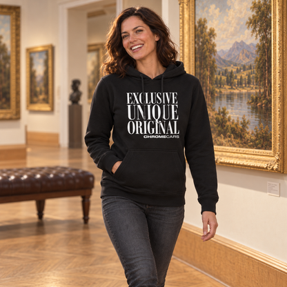 Eine Frau im schwarzen Hoodie mit weißem Schriftmotiv geht an einem goldgerahmten Landschaftsgemälde vorbei. Eine Hand steckt in der Kängurutasche, die andere hängt neben der dunklen Jeans.