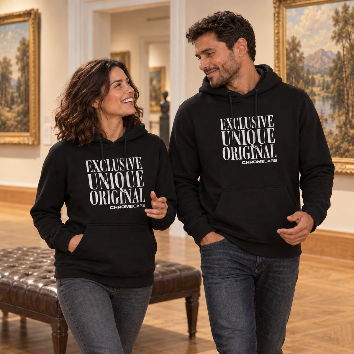 Eine Frau und ein Mann gehen in schwarzen Hoodies mit weißen Schriftmotiven nebeneinander durch eine Gemäldegalerie. Sie sehen einander an; die Frau hebt eine Hand vor dem Körper.