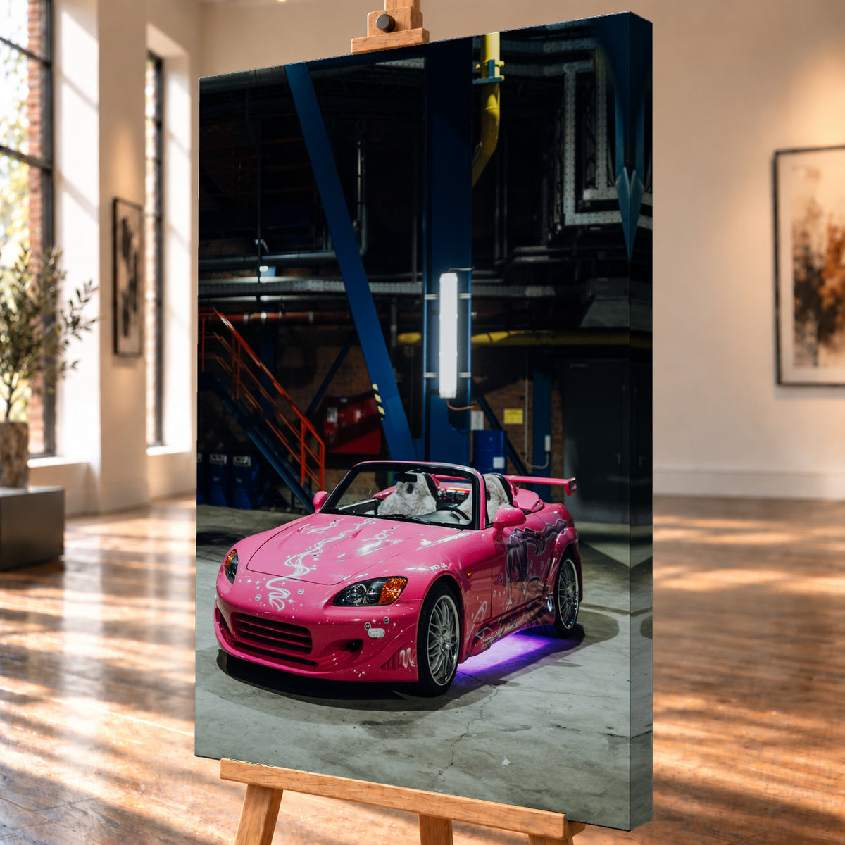 Schrägansicht eines hochformatigen Leinwandbilds als Produktvisualisierung auf einer Staffelei. Die rechte Seitenkante ist sichtbar; das Motiv zeigt den pinken Honda S2000 aus „2 Fast 2 Furious“ mit offenem Verdeck in einer dunklen Industriehalle.