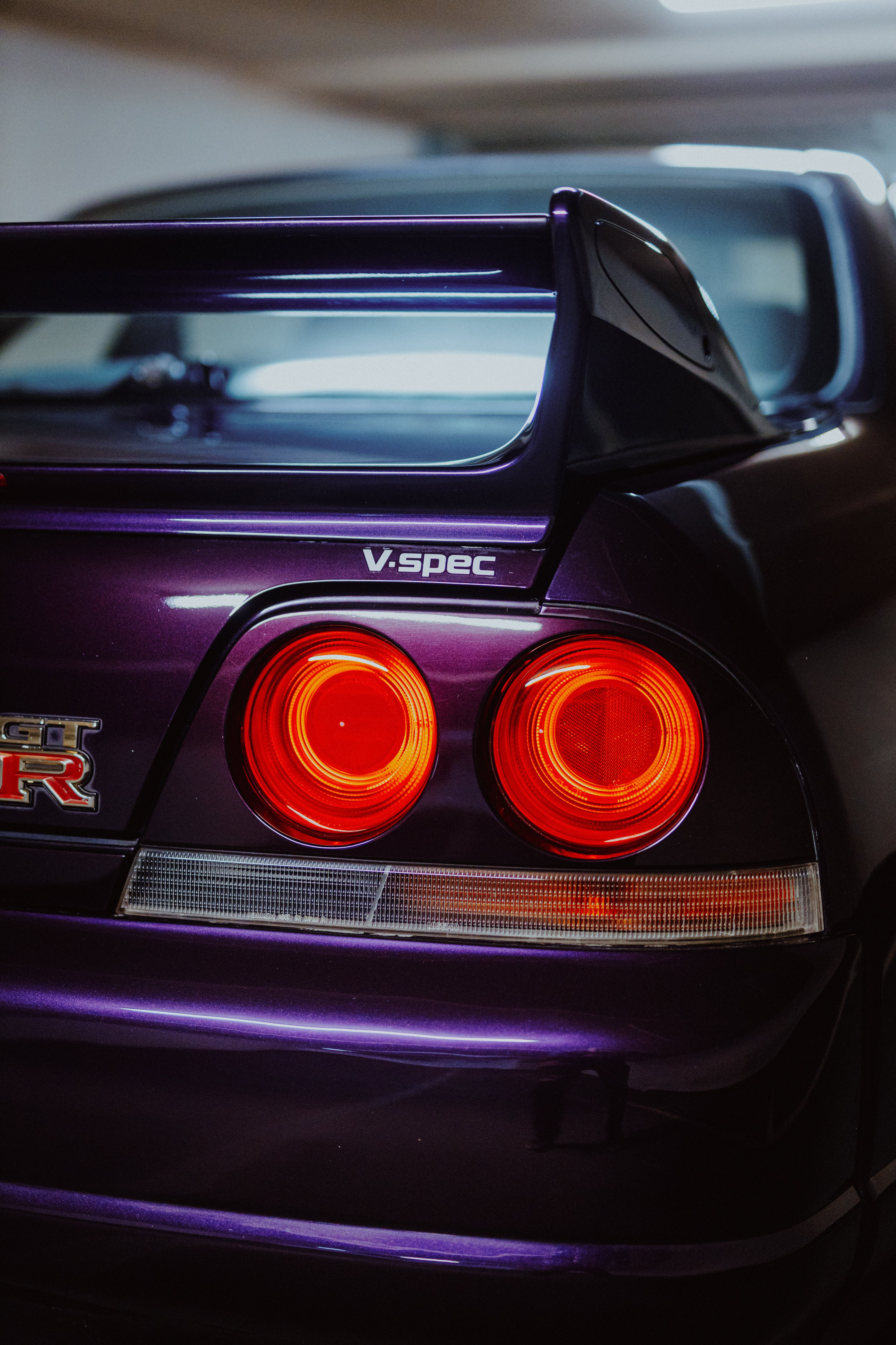 Violette Heckpartie des Nissan Skyline R33 GT-R NMP1 mit zwei runden roten Rückleuchten und Heckflügel.