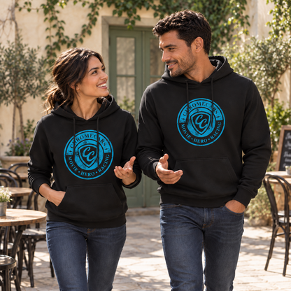Eine Frau und ein Mann gehen nebeneinander durch einen Café-Innenhof, beide in schwarzen Hoodies mit blauem CC-Stempelmotiv. Sie sehen einander an und halten jeweils eine Hand mit offener Handfläche nach vorn.