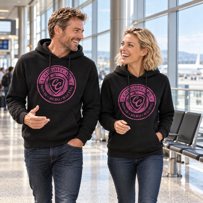 Ein Mann und eine Frau gehen in schwarzen Hoodies mit pinken CC-Stempelmotiven durch das Flughafenterminal und sehen sich an. Der Mann gestikuliert mit einer Hand.