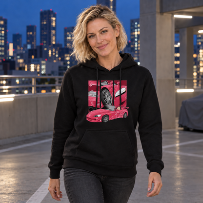 Frau im schwarzen Hoodie mit pinkem Frontmotiv blickt in die Kamera; hinter ihr liegen ein Parkdeck und beleuchtete Hochhäuser.